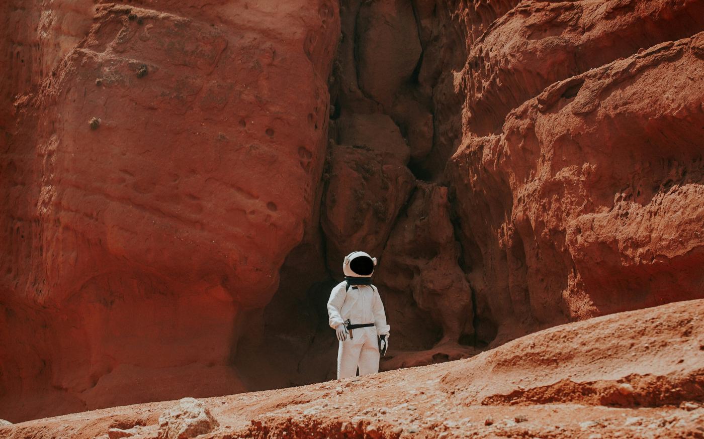 photography of astronaut standing beside rock formation during daytime by Nicolas Lobos courtesy of Unsplash.