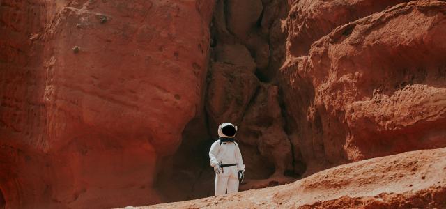 photography of astronaut standing beside rock formation during daytime by Nicolas Lobos courtesy of Unsplash.